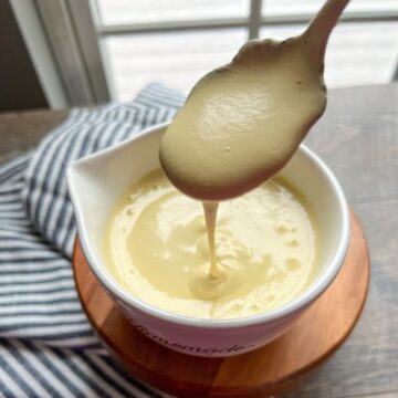 Cashew Cheese Sauce in white cup with spoon